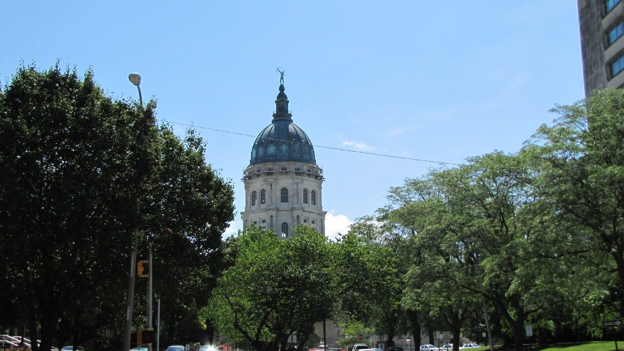 Kansas Statehouse dome rising over trees in Topeka
